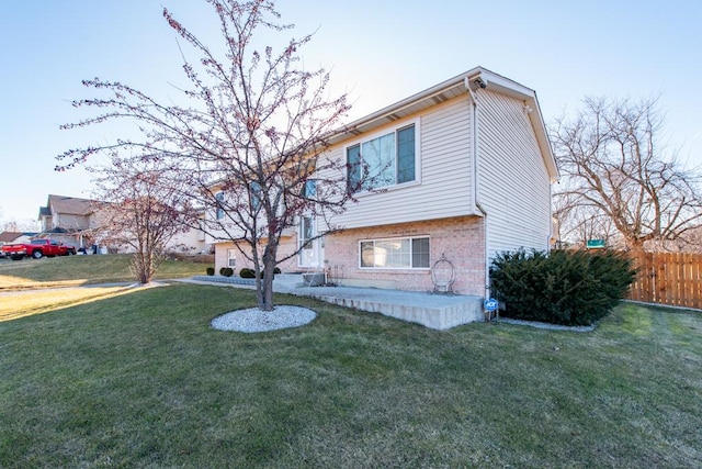 view of front of house with brick siding, fence, and a front lawn