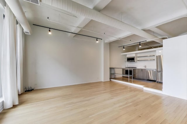 unfurnished living room with light wood-type flooring, baseboards, and track lighting