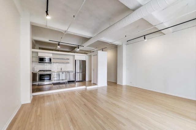 unfurnished living room with baseboards, track lighting, and light wood-style floors