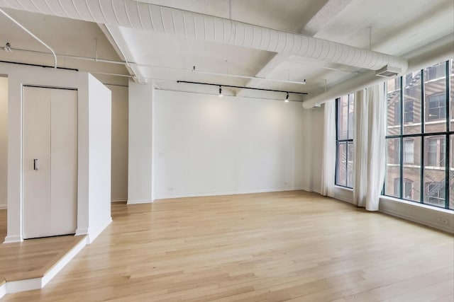 unfurnished room featuring baseboards, wood finished floors, visible vents, and track lighting