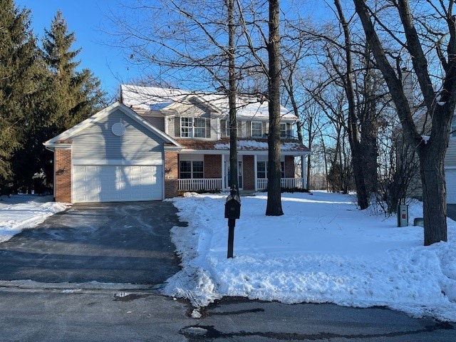 view of front of property with a garage, covered porch, brick siding, and aphalt driveway