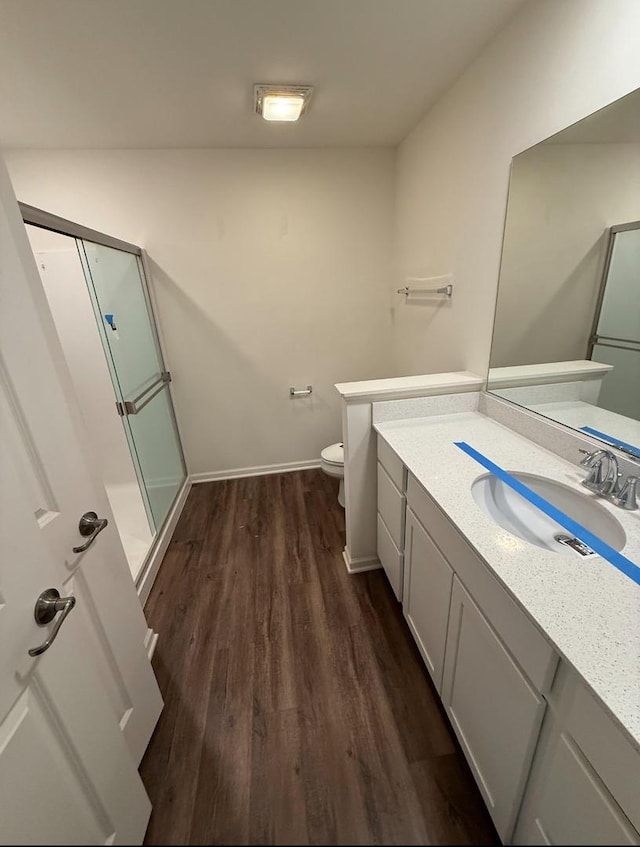 bathroom with toilet, vanity, hardwood / wood-style floors, and an enclosed shower