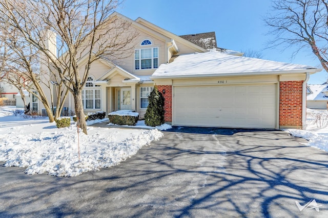 view of front of property with aphalt driveway, brick siding, and an attached garage