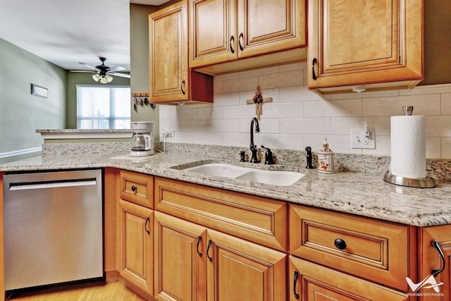 kitchen with a sink, light stone countertops, a ceiling fan, and dishwasher