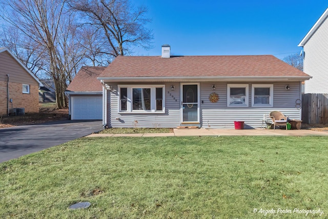 view of front of home with a front lawn, a chimney, and a shingled roof