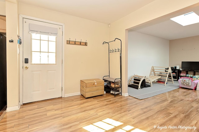 interior space featuring light wood finished floors, baseboards, and a skylight