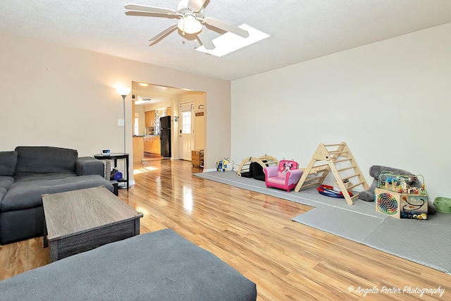 living room featuring a textured ceiling, wood finished floors, and a ceiling fan