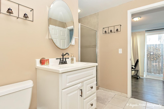 bathroom with toilet, a shower with shower door, vanity, baseboards, and tile patterned floors