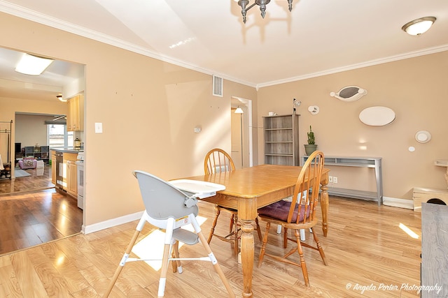 dining area featuring ornamental molding, light wood finished floors, visible vents, and baseboards