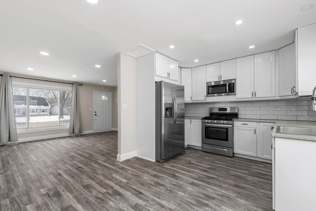 kitchen with white cabinetry, dark hardwood / wood-style floors, tasteful backsplash, and stainless steel appliances