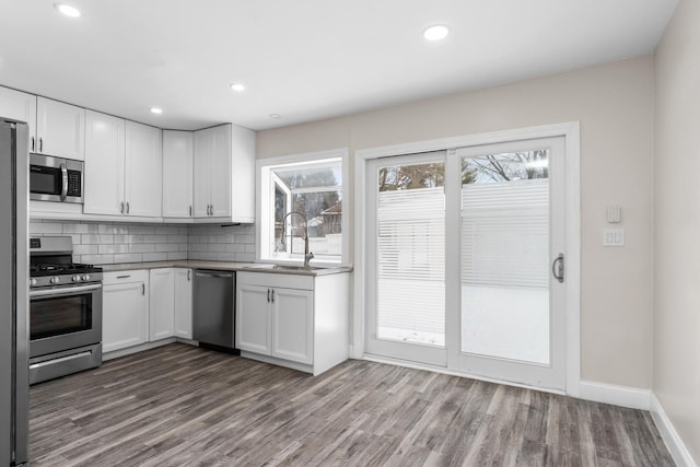 kitchen featuring light wood-type flooring, appliances with stainless steel finishes, white cabinetry, and sink