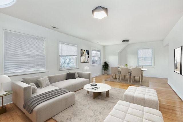 living area featuring visible vents, light wood-style flooring, and baseboards