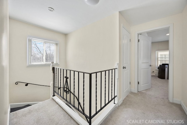 hallway featuring carpet, baseboards, plenty of natural light, and an upstairs landing