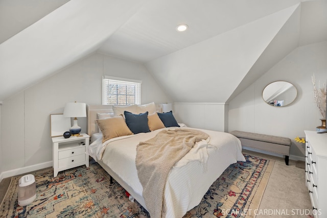 bedroom with baseboards, vaulted ceiling, and light colored carpet