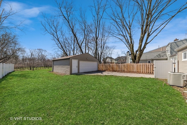 view of yard featuring a detached garage, fence, central AC, and an outdoor structure