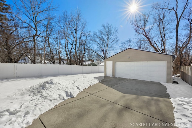 snow covered garage with a garage and fence