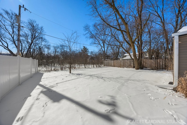 snowy yard with a fenced backyard