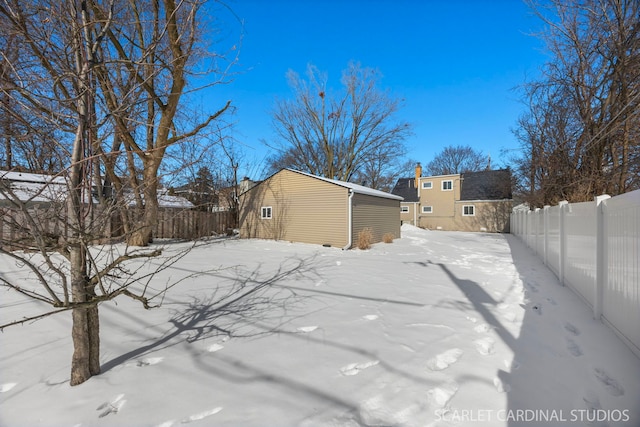 yard layered in snow with an outbuilding and a fenced backyard