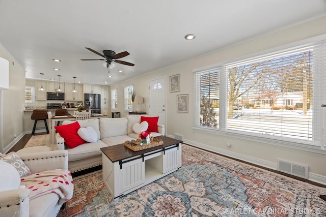 living room featuring baseboards, visible vents, a ceiling fan, and recessed lighting