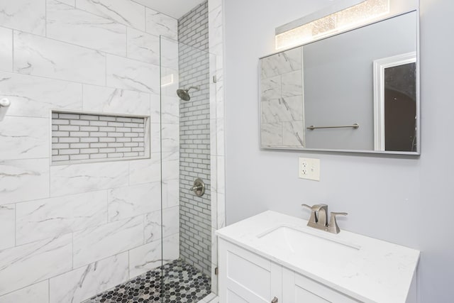 bathroom with tiled shower and vanity