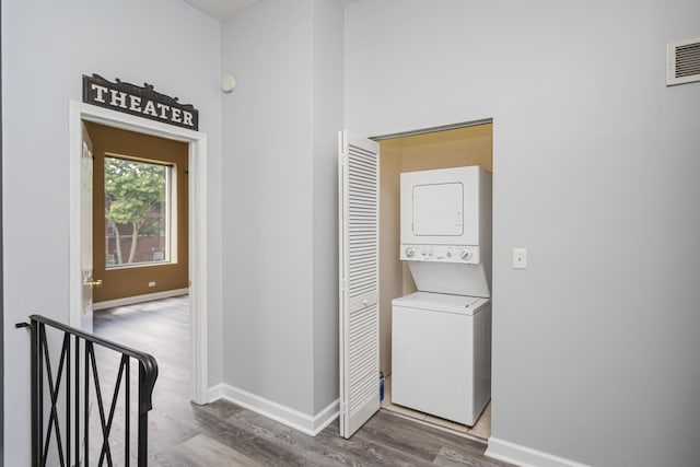 laundry room featuring stacked washing maching and dryer and hardwood / wood-style floors