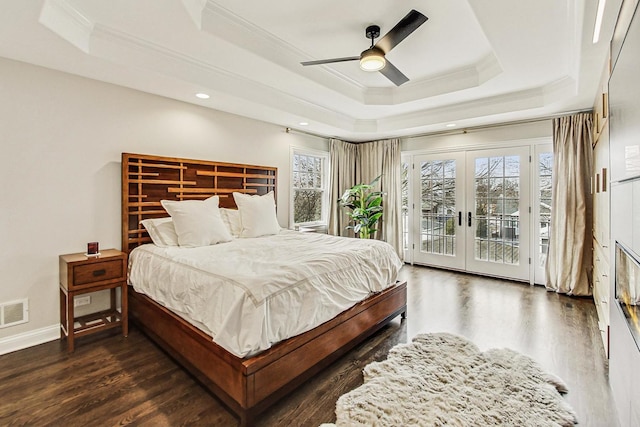 bedroom with access to exterior, multiple windows, a raised ceiling, and french doors