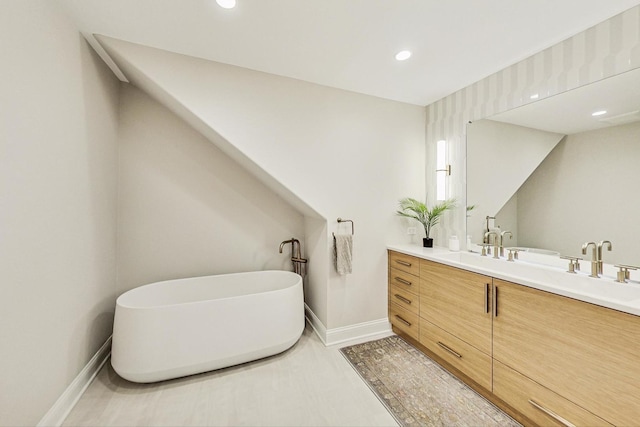 bathroom with recessed lighting, a freestanding tub, vanity, and baseboards