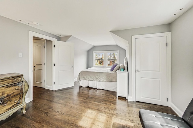 bedroom featuring lofted ceiling, dark wood-type flooring, and baseboards