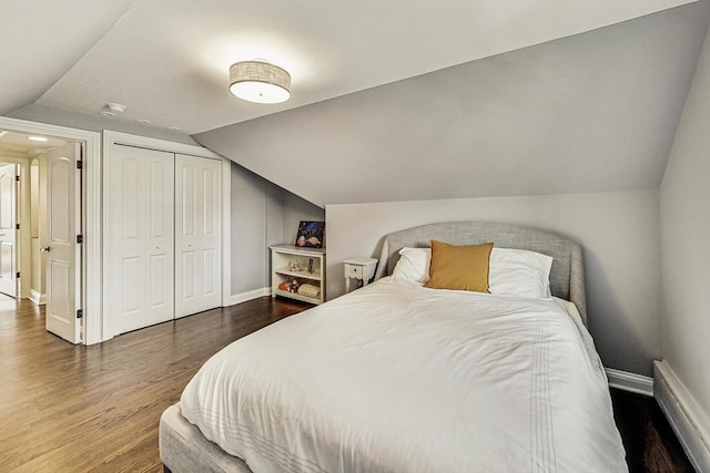 bedroom with dark wood-style floors, a closet, vaulted ceiling, and baseboards