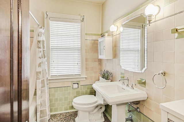 full bathroom featuring toilet, a shower with shower curtain, and tile walls