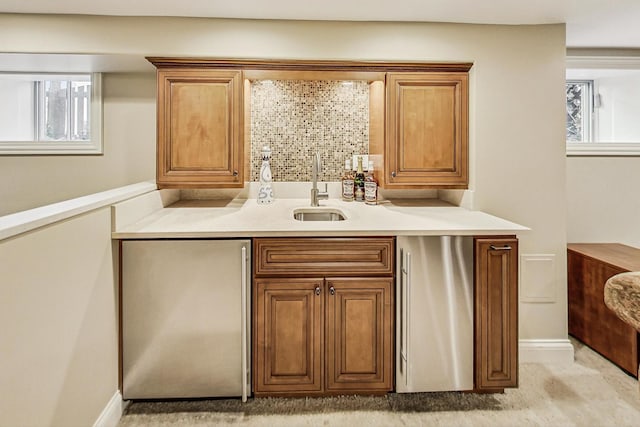 bar featuring a wealth of natural light, a sink, backsplash, and fridge