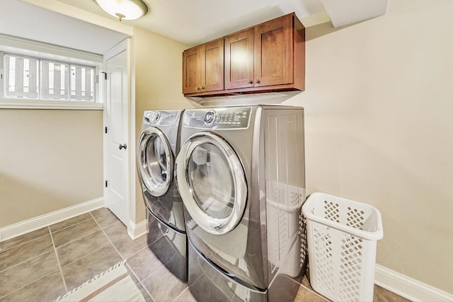 clothes washing area featuring washer and clothes dryer, light tile patterned flooring, cabinet space, and baseboards