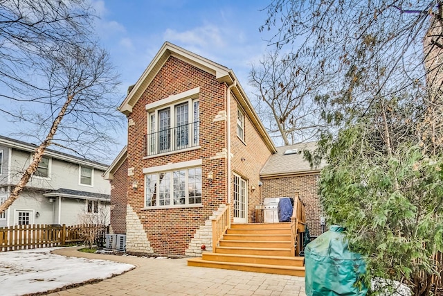 view of front of house with entry steps, fence, and brick siding