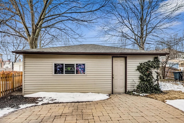 snow covered structure with an outbuilding and fence