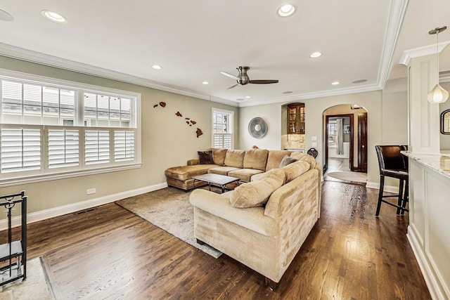 living area featuring ornamental molding, arched walkways, and plenty of natural light