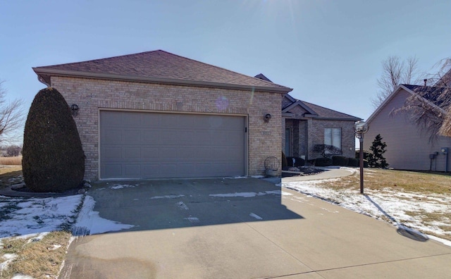 view of front of home featuring a garage, brick siding, driveway, and a shingled roof