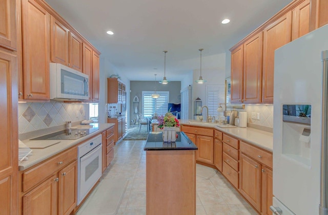 kitchen featuring decorative light fixtures, a kitchen island, a sink, white appliances, and a peninsula