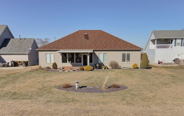 back of property featuring a shingled roof and a yard