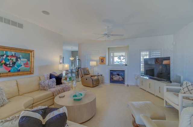 living room with light carpet, ceiling fan, a glass covered fireplace, and visible vents