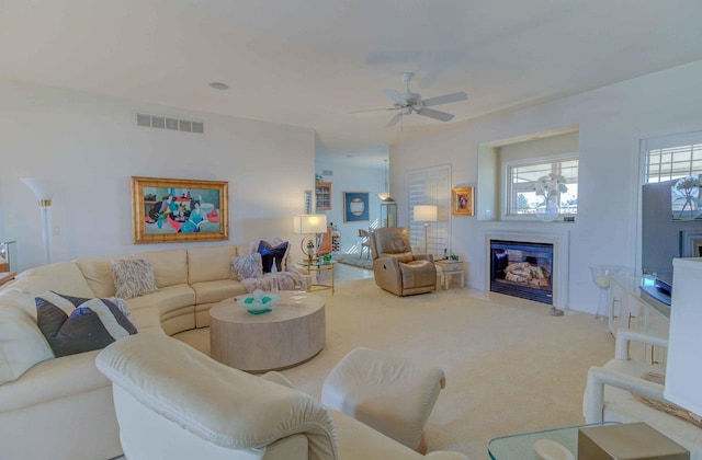 living room featuring ceiling fan, carpet, a glass covered fireplace, and visible vents