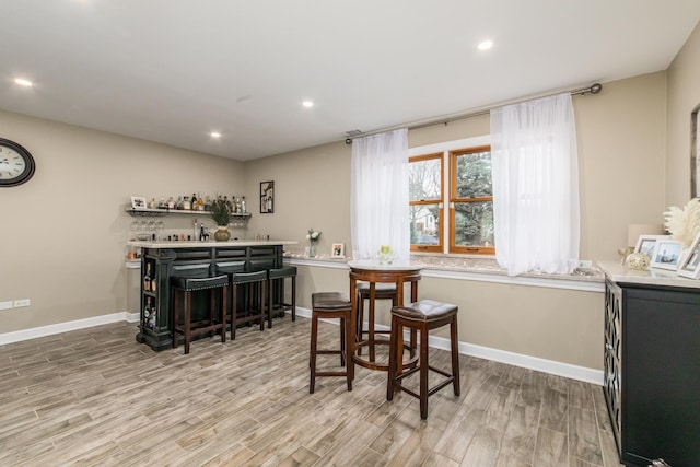 dining space with light hardwood / wood-style flooring and bar area