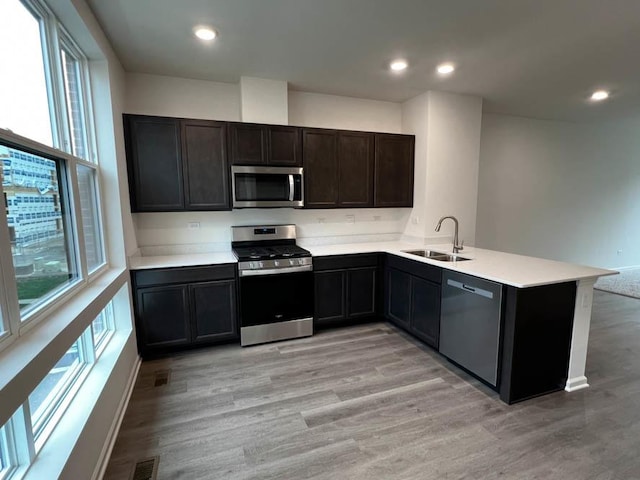 kitchen featuring light hardwood / wood-style floors, appliances with stainless steel finishes, sink, and kitchen peninsula