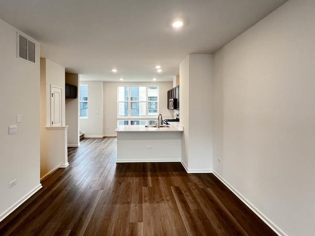 unfurnished living room featuring dark wood-type flooring and sink