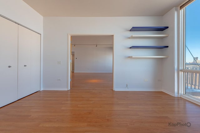 unfurnished bedroom with light wood-type flooring, a closet, and baseboards