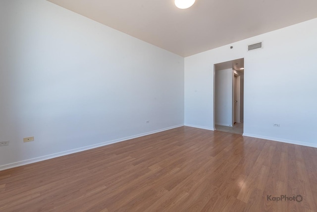 unfurnished room with baseboards, visible vents, and wood finished floors