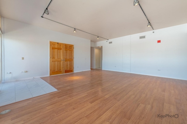 spare room featuring light wood-type flooring, visible vents, and track lighting