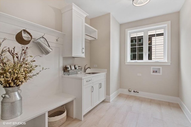 clothes washing area with cabinets, sink, light hardwood / wood-style floors, and hookup for a washing machine