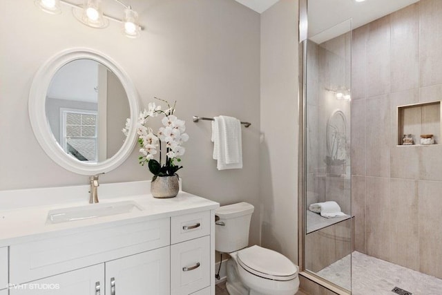 bathroom with vanity, tiled shower, and toilet