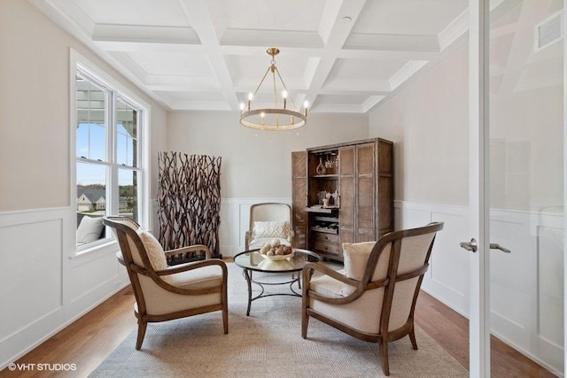 sitting room with beam ceiling, a chandelier, coffered ceiling, and hardwood / wood-style floors