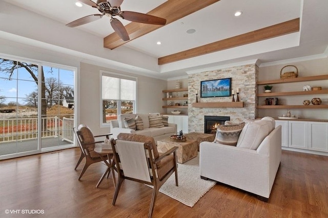 living room featuring beam ceiling, ceiling fan, wood-type flooring, and a fireplace